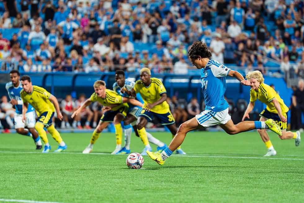 Football match action with a player striking the ball toward goal